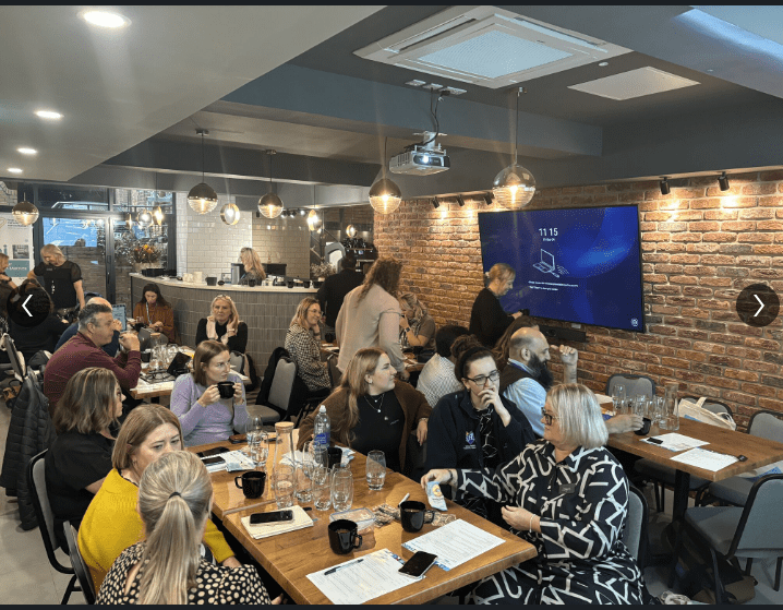 A group of Digital and Transformation Leads discussing their collective challenges, sharing ideas how to overcome.  Some sitting at tables, others facilitating the conversation